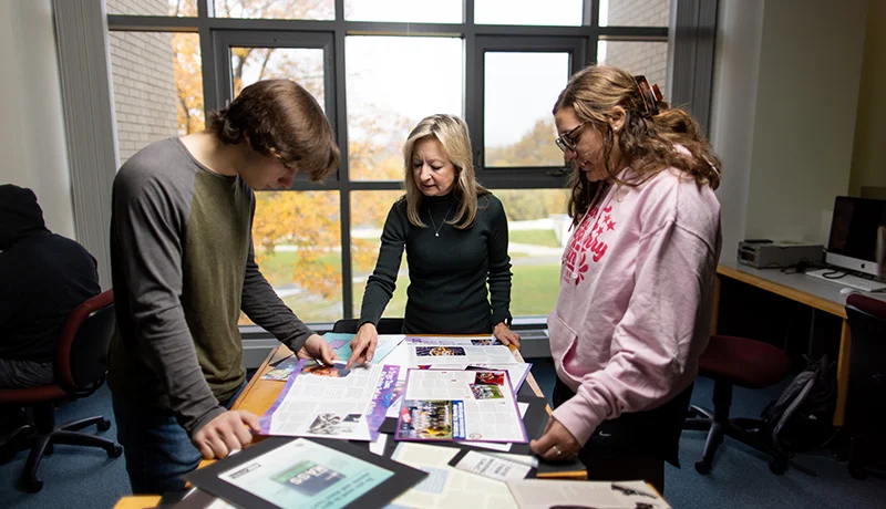 students and a professor looking at marketing materials