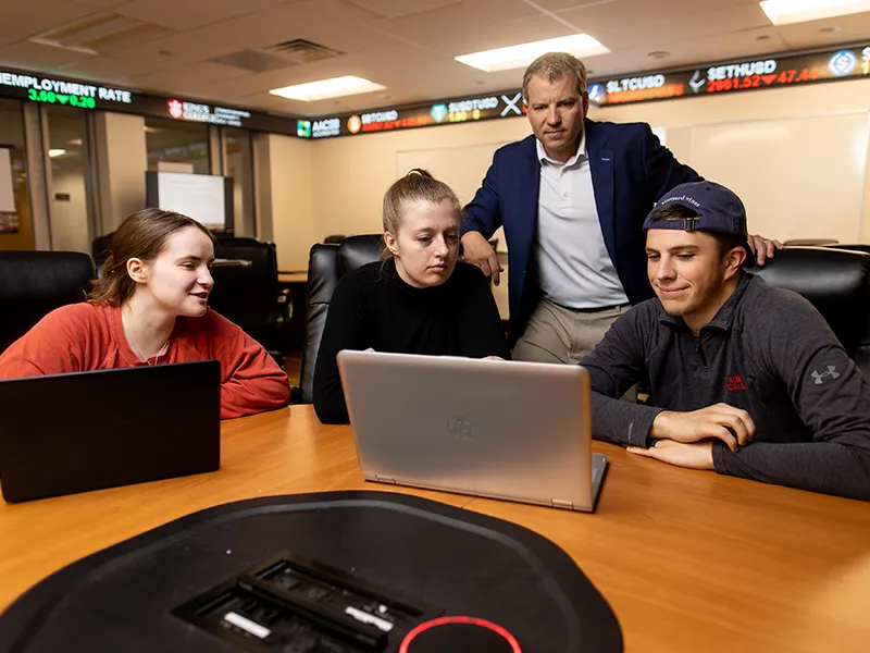 students and professors looking at a laptop