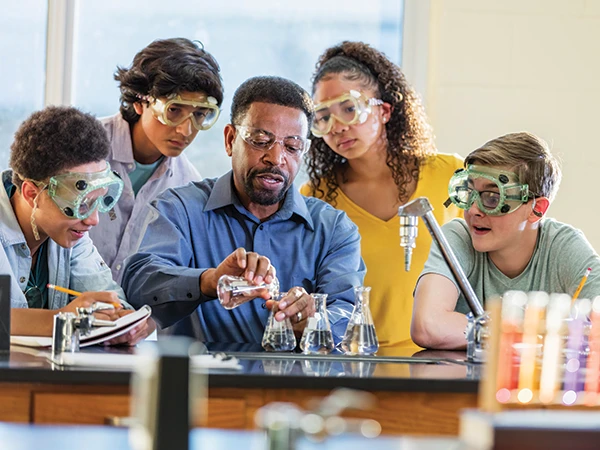 teacher pouring fluids into a beaker