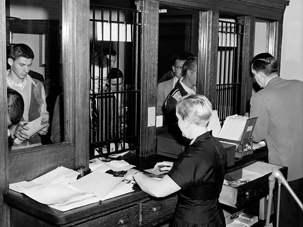 archival photo of students lined up outside the registrar