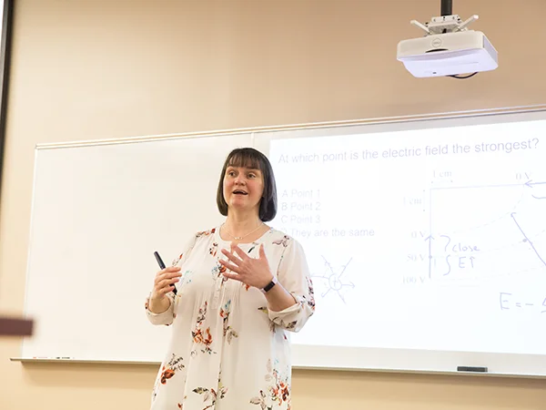 a professor lecturing in front of a whiteboard