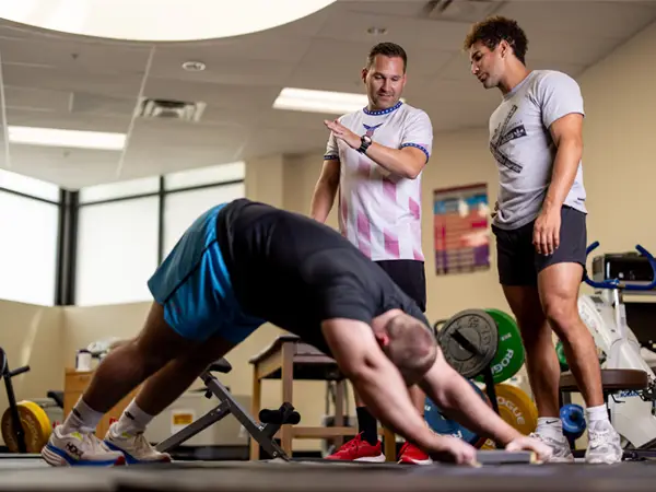 professor demonstrates proper form for an exercise using a hand motion