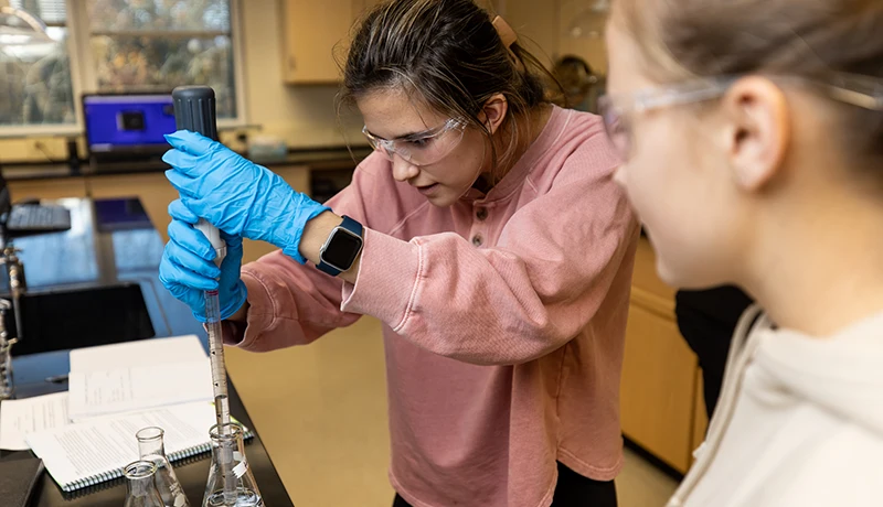 students filling a beaker in a lab