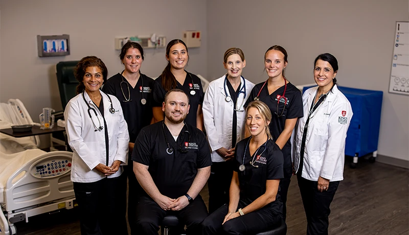 nursing school graduates pose for a group photo in scrubs