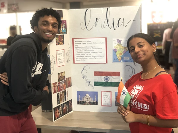 two students posing with an India poster