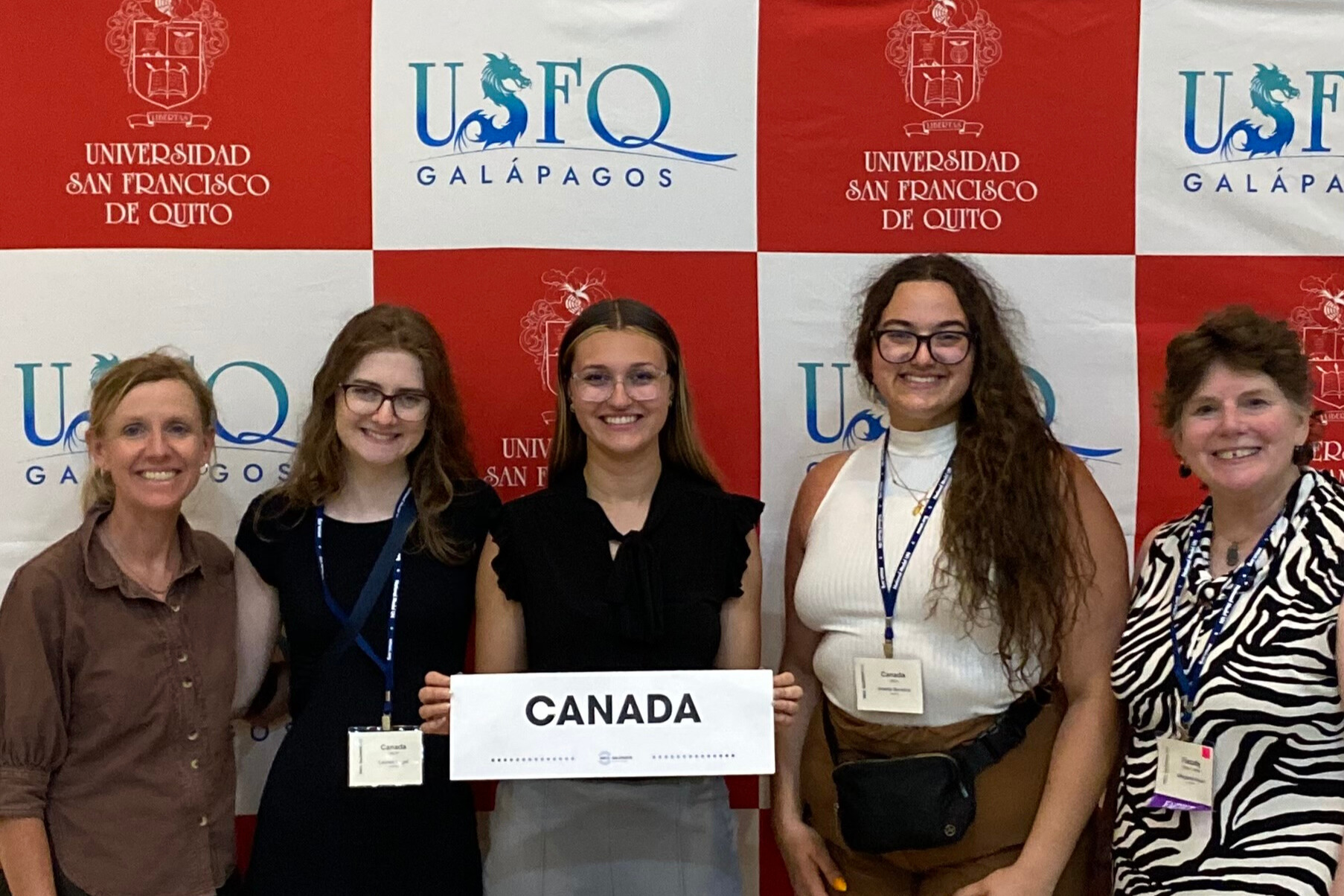 Facility and students posing at conference as they represent Canada by holding a sign.