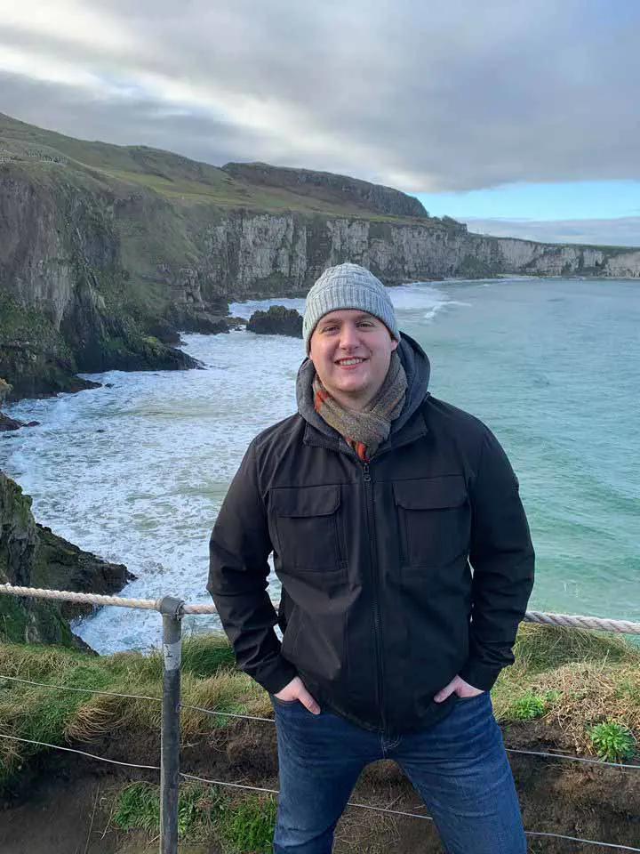 man stands in front of cliffside in Ireland